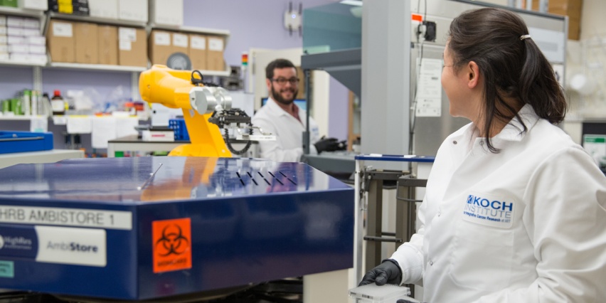 two scientists working next to a robotic arm