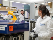 two scientists working next to a robotic arm